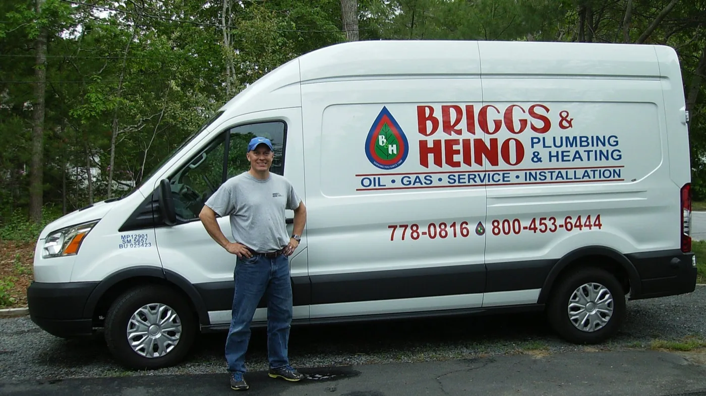 Briggs & Heino technician standing in front of a company plumbing and heating service van